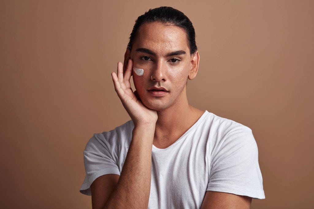 Non-binary person applying cream to face with possibly Botox, Retinol and AHA