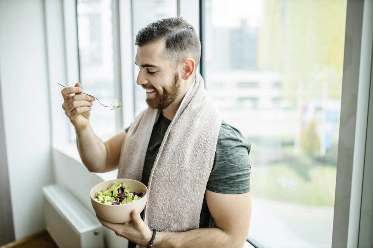 Smiling fit Caucasian man eating a salad