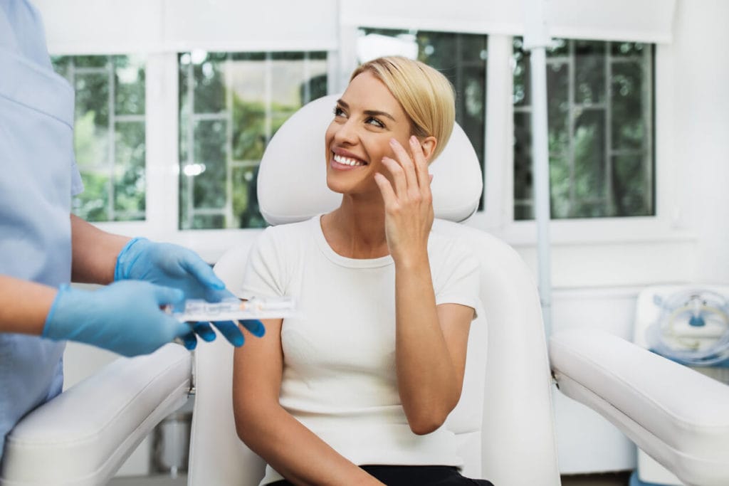 Woman smiling up at her doctor after getting dermal fillers