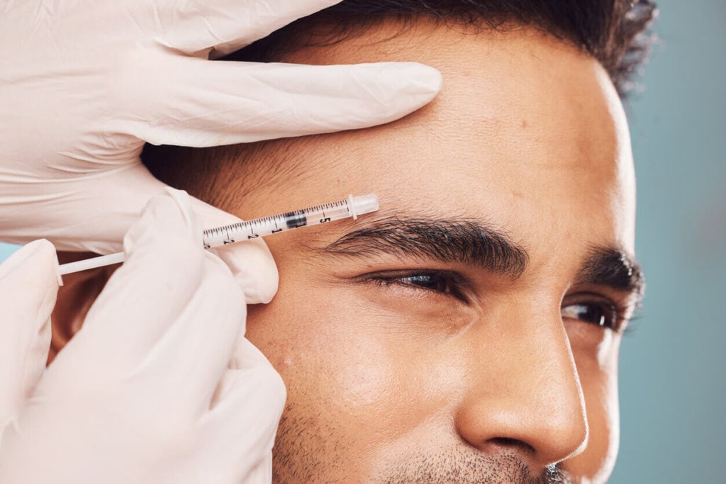 Closeup of a Botox London injection right above a man’s eyebrow