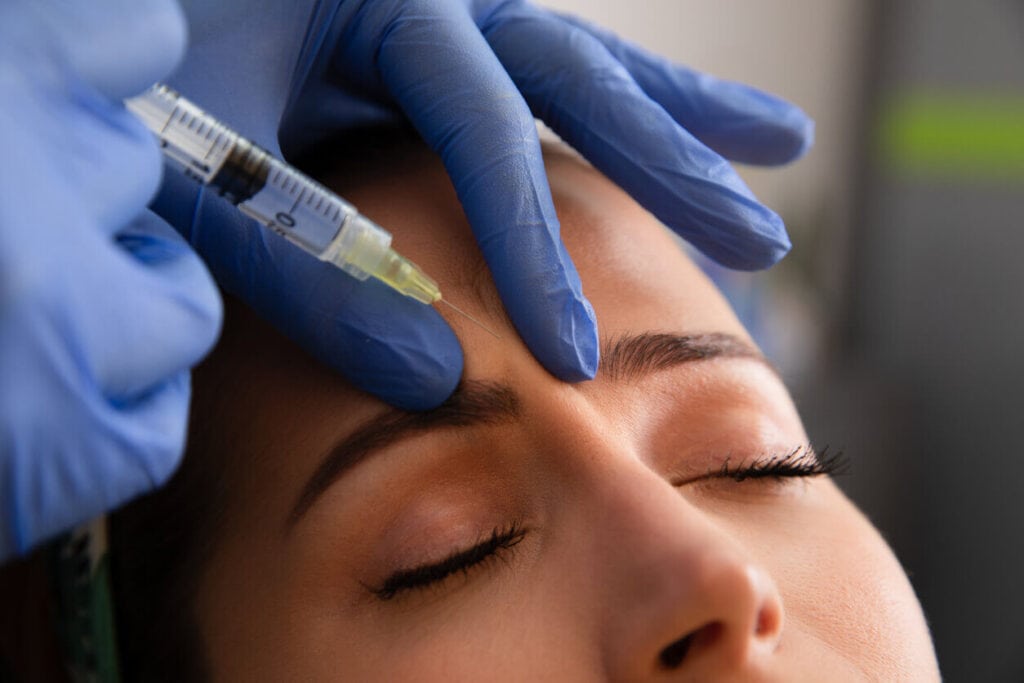 Getting Botox and dermal fillers - Woman getting a Botox injection for her forehead lines.
