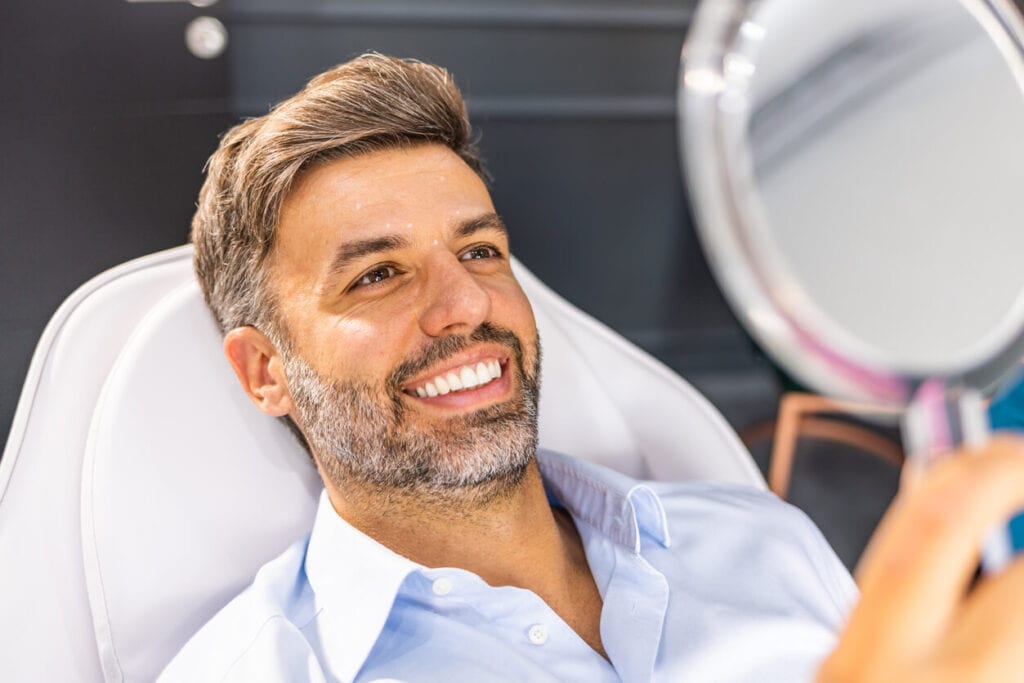 Middle-aged man looking at the mirror and checking the result of the Botox treatment