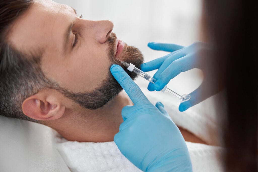 A man lying down and getting injected by fillers