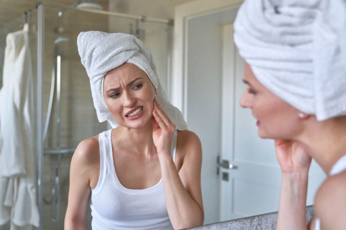 Female holding side of jaw due to jaw pain from teeth grinding