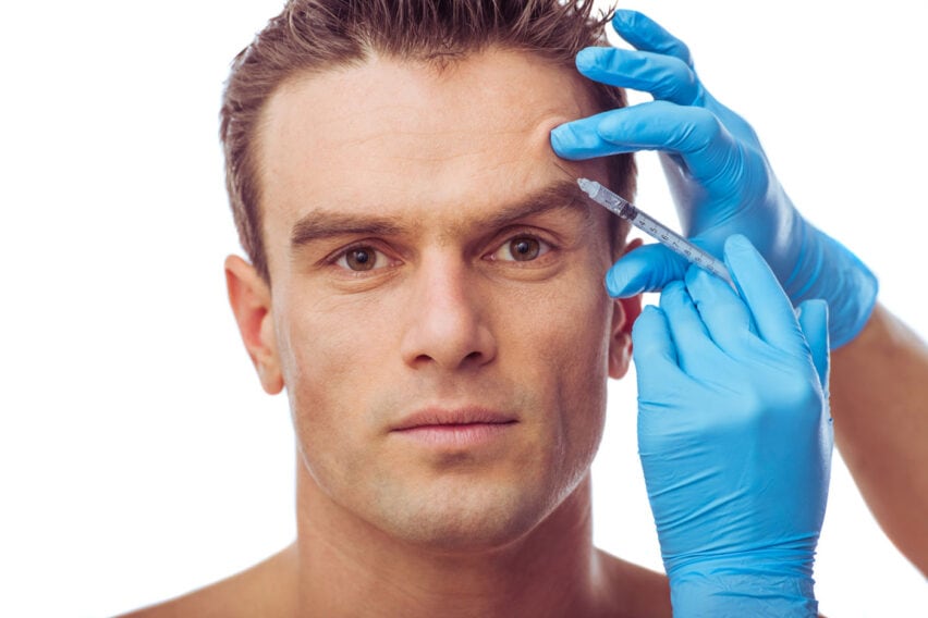 Headshot of middle aged male having injections of botox, to treat wrinkles on forehead in Soho.